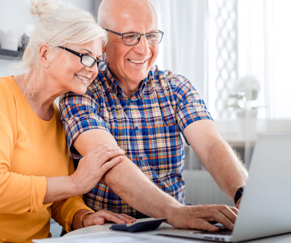 Retired couple smiling and looking at a computer